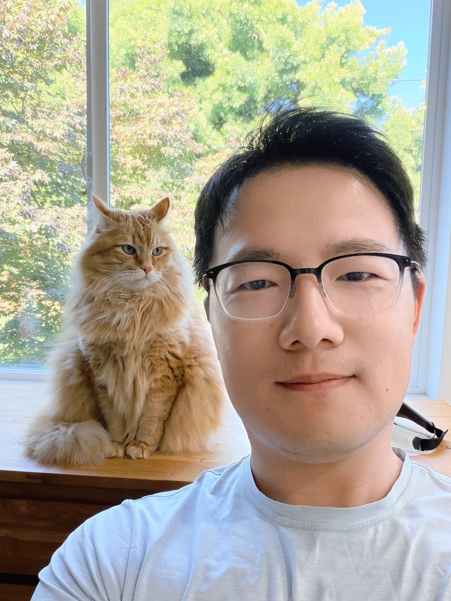 Carson Chen with his cat by a sunlit window